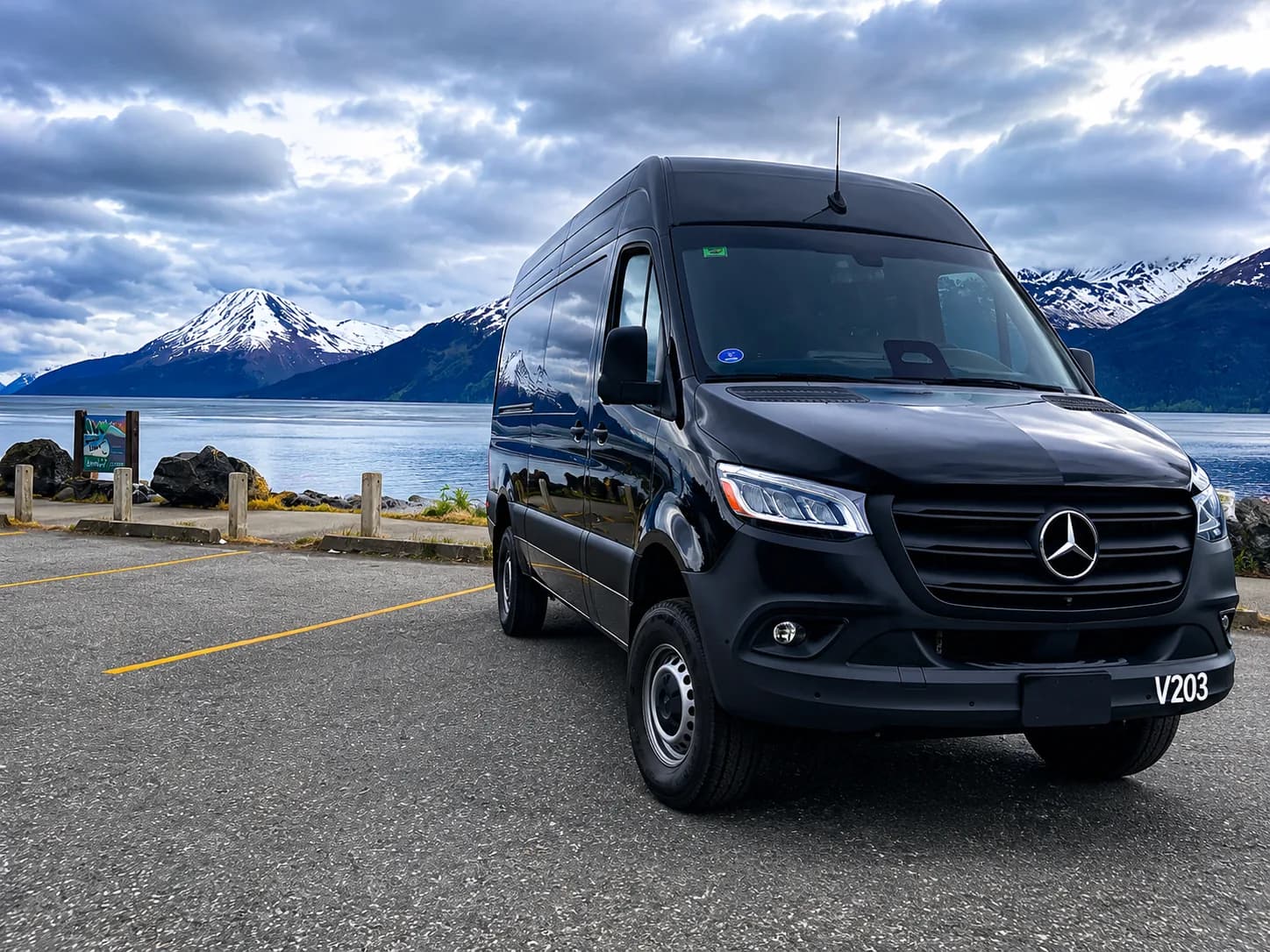 Black Mercedes-Benz Sprinter Van by a turquoise glacier lake under dramatic clouds, Turnagain Arm, Alaska