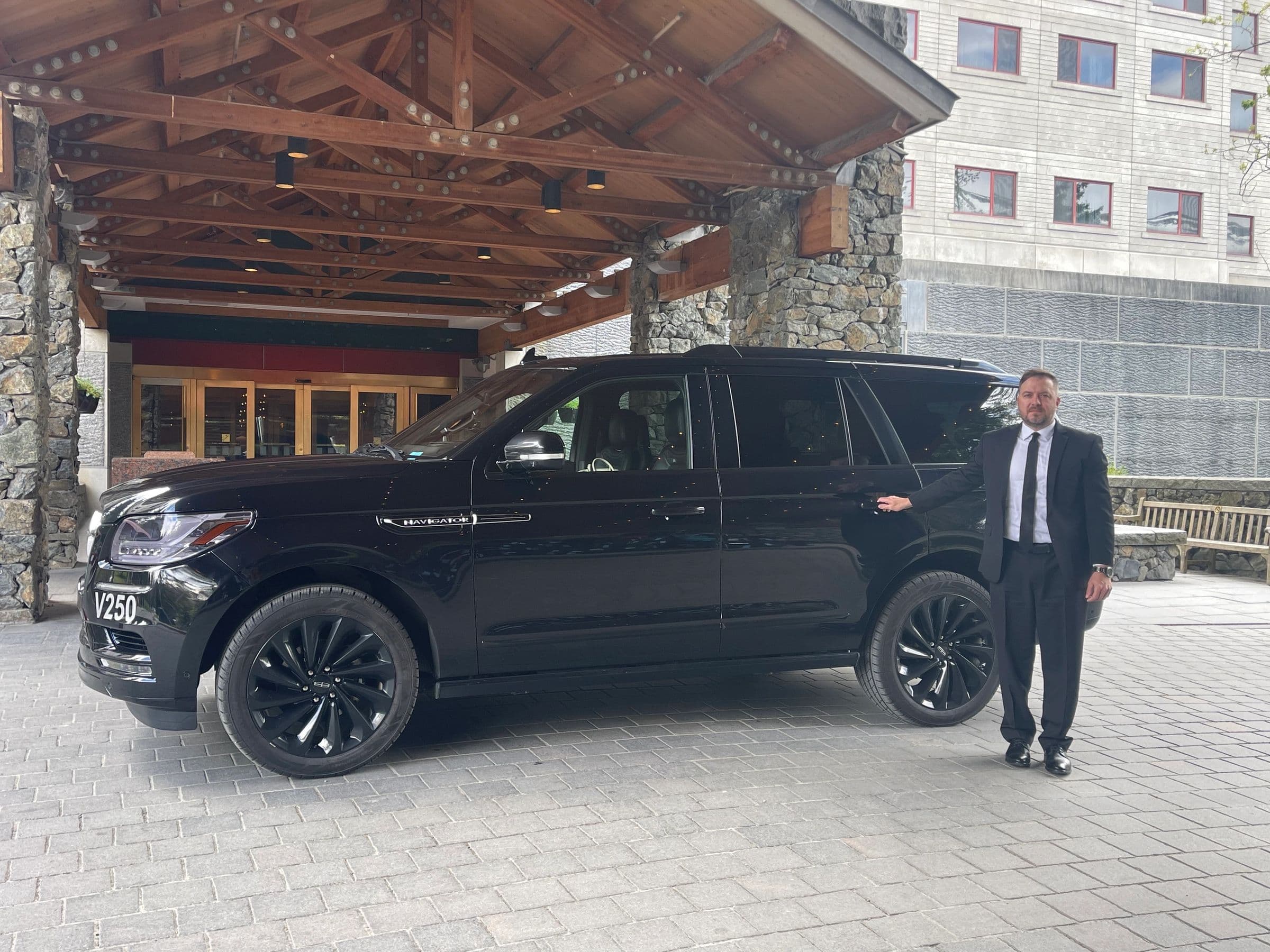 Jason Anderson, owner and chauffeur, standing beside his black Lincoln Navigator at the resort entrance in Girdwood, Alaska